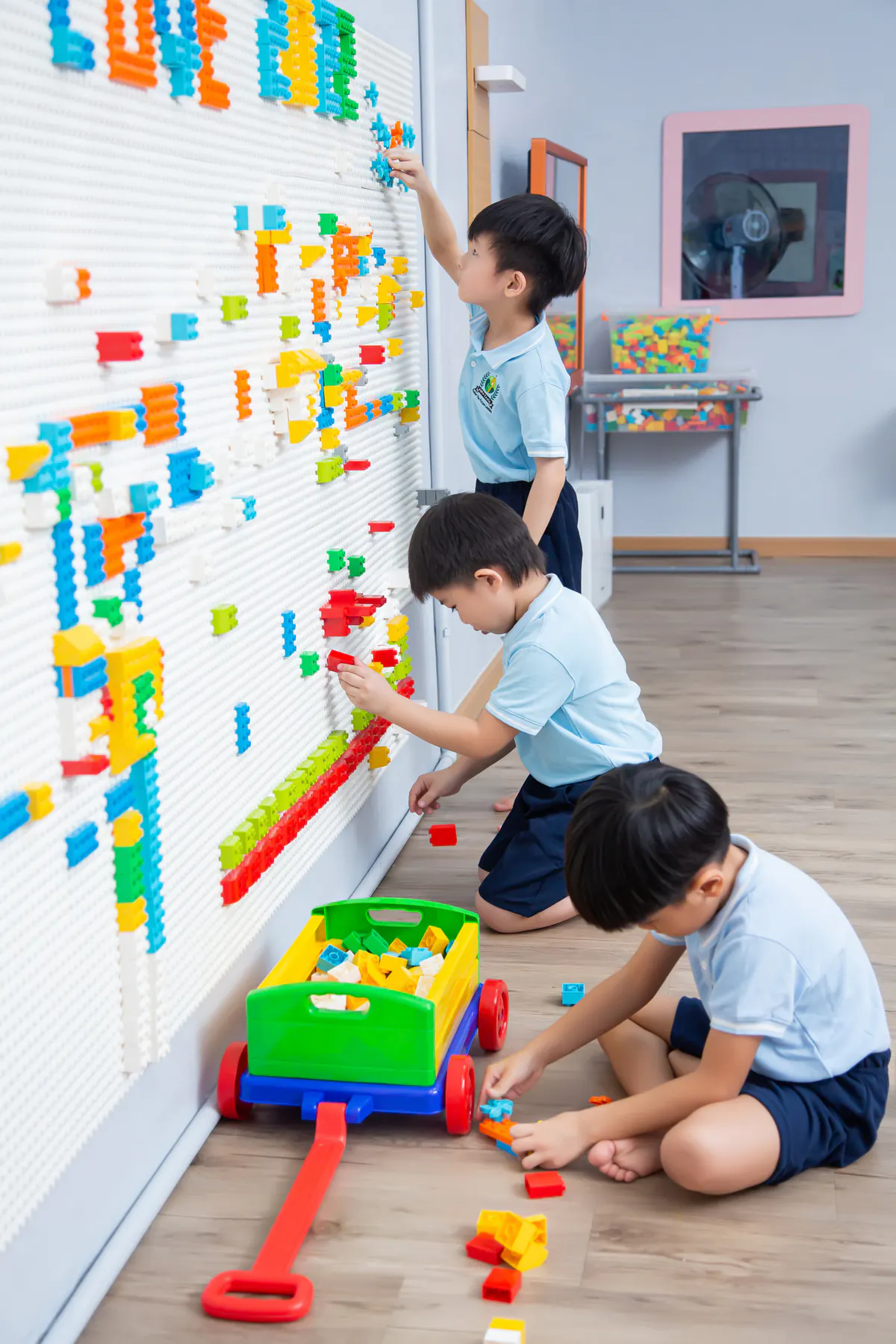 Children collaborating on a large construction wall